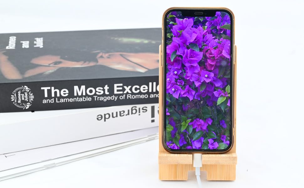 Smartphone displaying purple flower wallpaper, mounted on a wooden stand with natural grain finish.