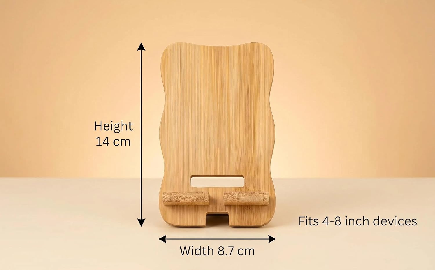 Text reads "Height 14 cm", "Width 8.7 cm", "Fits 4-6 inch devices". Wooden phone stand with curved wavy top design, natural light wood finish, rectangular base with device slot, dimensions labeled on sides.