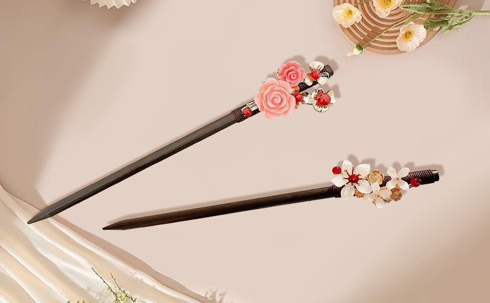 Decorative dark pen or stylus adorned with pink floral elements, photographed against beige backgrounds with books, showing multiple angles and details.